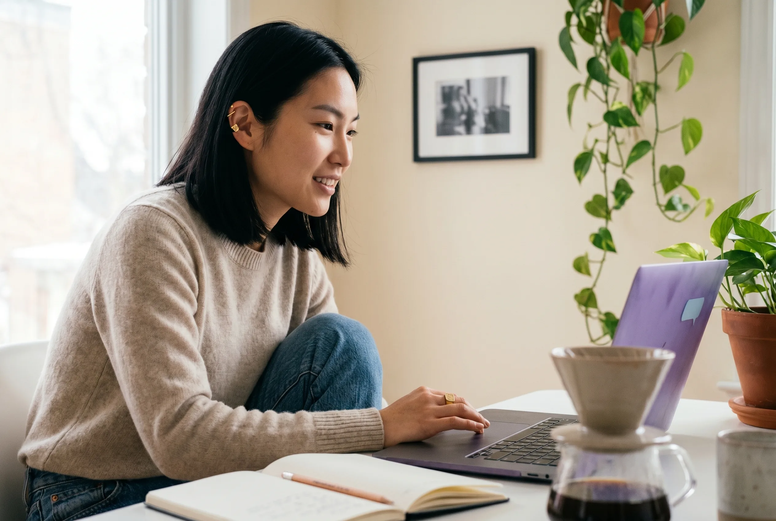 Mira Chen at her Toronto home-office workstation in the moment she finishes signing up for Playcut, right hand on the trackpad, soft north-facing window light catching her gold ear cuff and signet ring, Playcut Imagen 4 generation.